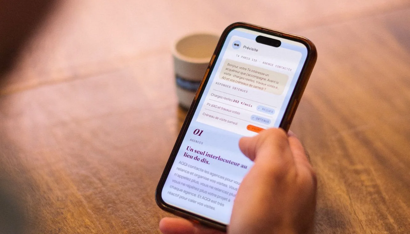 Un professionnel consulte AQQI sur son téléphone, à côté d’une tasse AQQI.